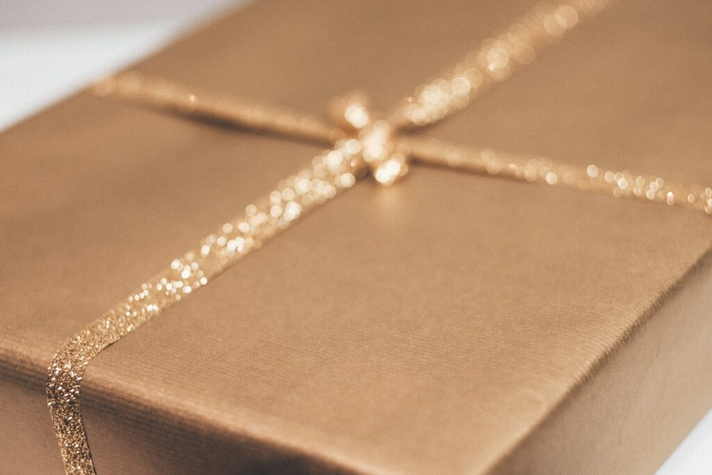 Brown wrapping paper hides a present and is tied with gold glittery ribbon